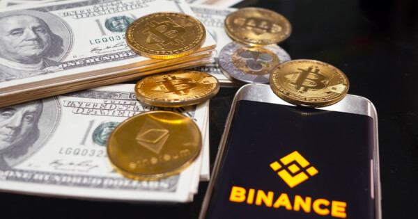 Binance logo with American dollar and Bitcoin, XRP, and Ethereum crypto assets